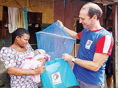 Managing Director, Total Nigeria, Mr. Alexis Vovk (right), presenting a LLIN to a beneficiary in Ibafon community.